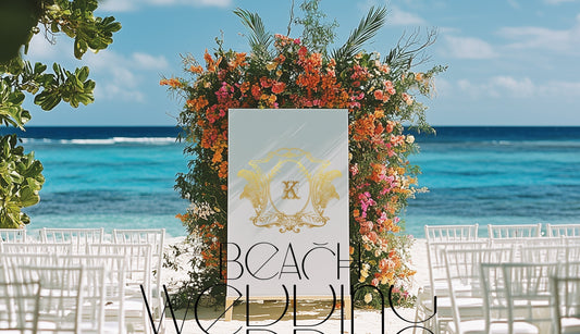 Elegant beach wedding setup featuring white chairs and a personalized welcome sign with couple’s monogram