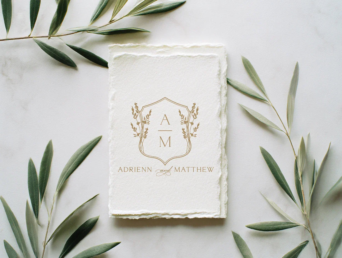 Elegant gold wedding monogram displayed on handmade deckled paper, custom wedding crest design