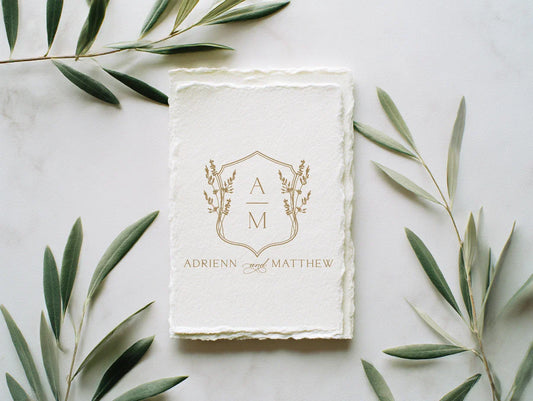 Elegant gold wedding monogram displayed on handmade deckled paper, custom wedding crest design