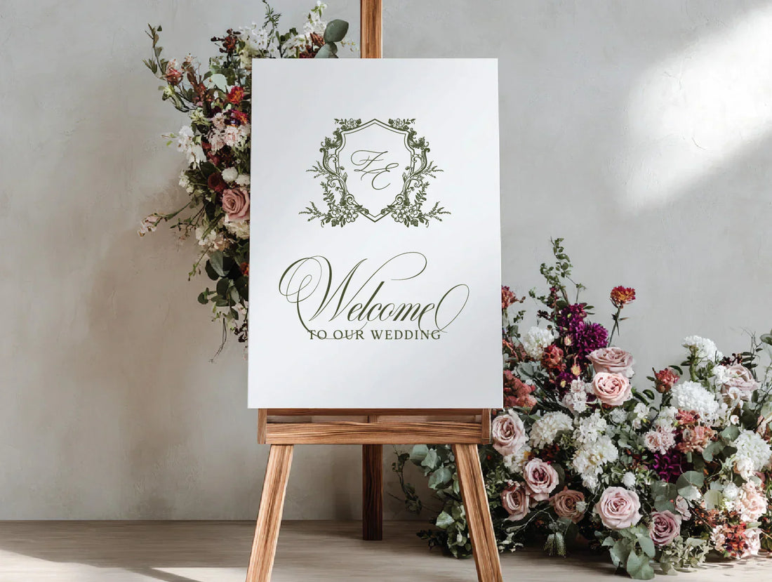 legant wedding welcome sign with fine art monogram crest on a wooden easel, surrounded by pastel and burgundy floral arrangements, luxury décor by LinvitInstant